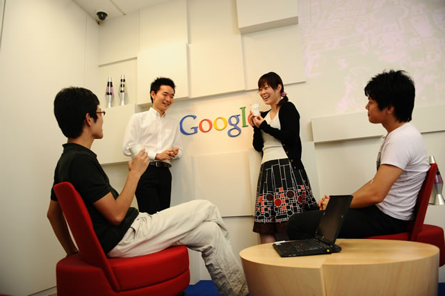 壁にGoogle のロゴがあって、4人の方が楽しく話している様子を示す画像。